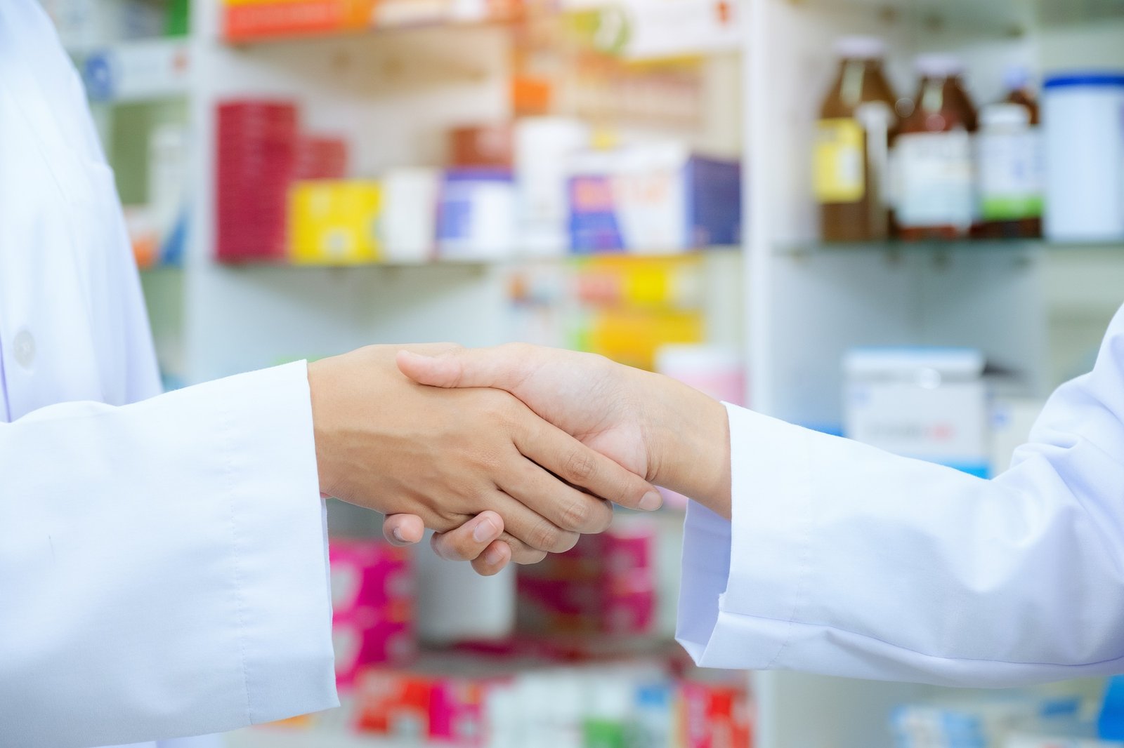 Drug store of pharmacist shaking hands with a client at the pharmacy